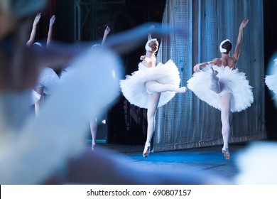 Performance, Culture, Scenery Concept. Gorgeous Ballerinas, Wearing Costumes Of Swans For World Known Ballet, As Light As Feathers Jumping And Floating Above The Stage Of The Theater