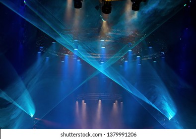 Performance moving LED Par lighting on construction light beam ray downward in blue color with Laser smoke graphic, on Concert and Fashion Show stage ramp, low light exposure with grain and noise