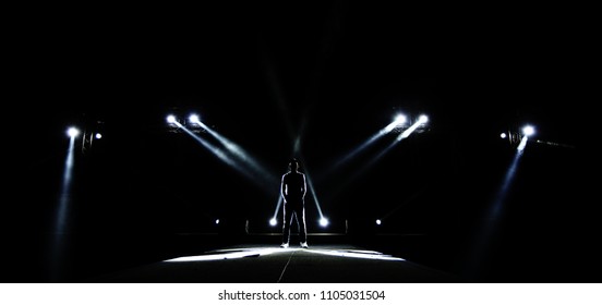 Performance moving lighting on construction light beam ray downward to Man on Stage as Leader Superstar, Silhouette of Male surround with Light, Dark Low Exposure, concept Unique Confidence