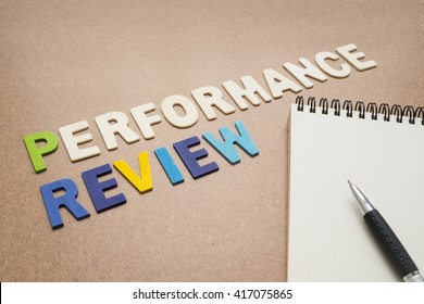 Performance Review Text With Open Spiral Notebook And Pen On Brown Background - Concept Of Quality Measurement