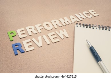 Performance Review Text With Open Spiral Notebook And Pen On Brown Background - Concept Of Quality Measurement