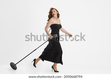 Performance time. In a hurry. Side view portrait of female singer carrying microphone and running away isolated over white background. Concept of art, music, concert, inspiration, culture, ad