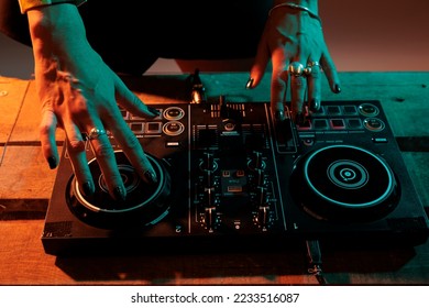 Performer artist mixing sounds at dj turntables, using audio equipment to play music and do musical remix performance. Having fun with volume instrument, nightclub party. Close up.