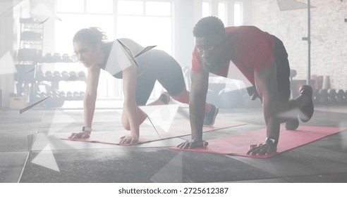 Performing two exercise partners in athletic wear holding plank at gym, with red mats and watches. Workout, fitness, training, duo, couple, studio, daylight