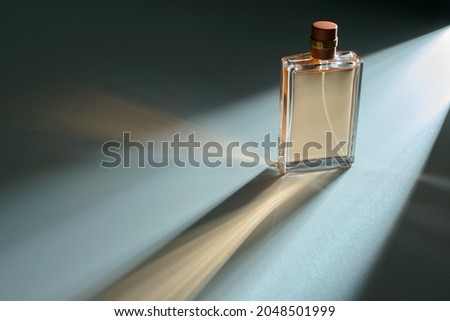 Perfume bottle with automatic dispenser on a blue background and a beautiful light effect. Perfume, cosmetic branding concept. Eau de parfum, luxury beauty brand