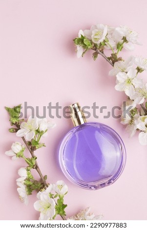 Perfume bottle and branch blooming cherry. Concept of expensive perfume and cosmetics. Floral fragrance for women. Perfume spray. Modern luxury lady parfum de toilette