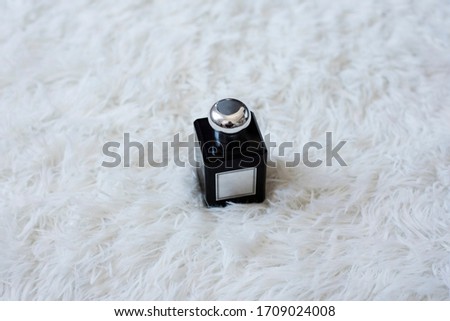 Perfume bottle in dicey shape with white label and silver metallic cap on white background. Fluffy and clean background. Minimal concept.