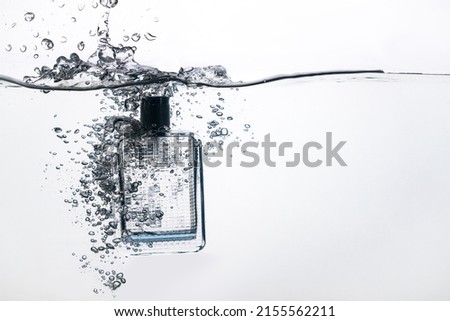 perfume bottle dropped into water on a white background