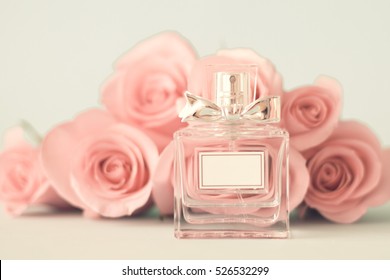 Perfume bottle in front of pink roses