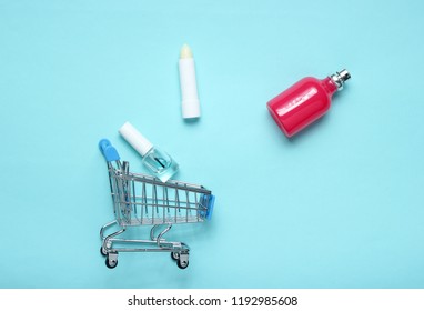 Perfume bottle, lipstick in a shopping cart on a blue pink pastel background. minimalism, the concept of beauty, accessories