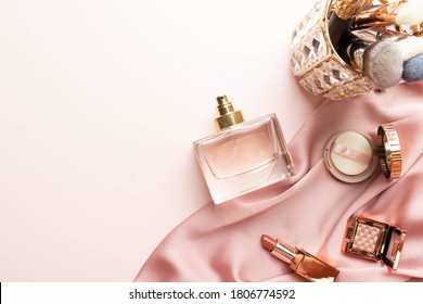Frasco de perfume con cosméticos de maquillaje sobre fondo de tela plegada de seda rosa. Un perfume de producto de belleza cosmética. Piso plano.