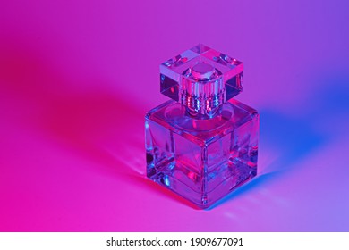 Perfume bottle with on neon light background. Blank perfumery mockup, spa branding concept.Glamour fragrance, eau de parfum.