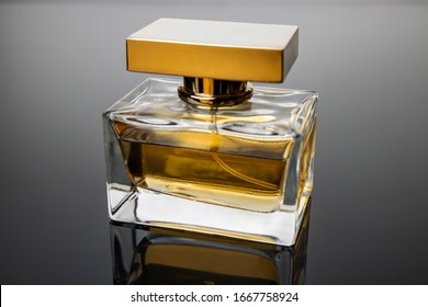 Perfume bottle in the rays of gray light on a black background. The play of light on a perfume bottle, can be used as a magazine and commercial photo with place for text or design