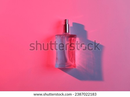 Perfume bottle in red blue neon light with shadow and reflexes. Beauty and fashion still life