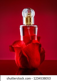 Perfume Bottle In Rose Petals On Red Background. Product Photography Presentation On Red Pasiion Background 