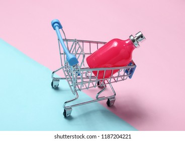 Perfume bottle in a shopping cart on a blue pink pastel background. minimalism, the concept of beauty, accessories