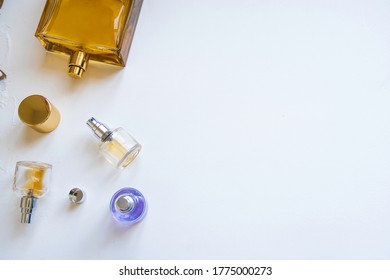 Perfume Bottles Of Different Colors And Sizes Are Scattered And Stand On A White Background. Elite Niche Perfumery In Full And Travel Version.