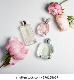 Perfume Bottles With Flowers On Light Background. Perfumery, Cosmetics, Fragrance Collection. Flat Lay