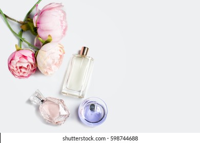 Botellas perfumes con flores sobre fondo claro. Perfumería, cosmética, colección de fragancias. Espacio libre para texto.