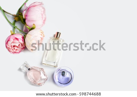 Perfume bottles with flowers on light background. Perfumery, cosmetics, fragrance collection. Free space for text.