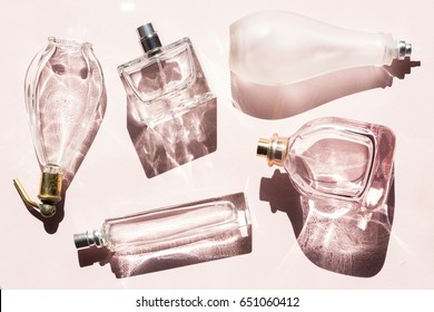 Perfume bottles with the shadows on pink background