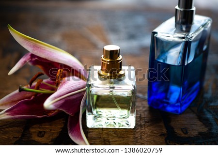 Perfume bottles surrounded by lily petals. Eau de toilette. Eau de parfum. Parfum with flowers on wooden background.