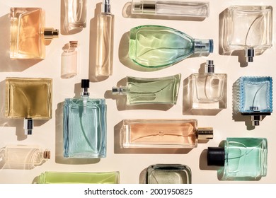 perfume bottles. a lot of transparent multicolored glass bottles of cosmetics, on a beige background. art composition flat lay still life
