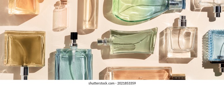 perfume bottles. a lot of transparent multicolored glass bottles of cosmetics, on a beige background. art composition flat lay panoramic - Shutterstock ID 2021853359