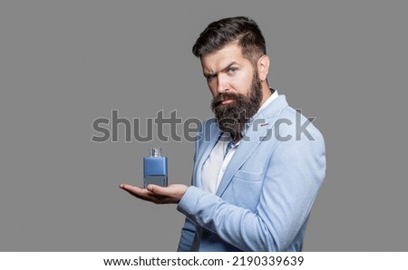 Perfume or cologne bottle and perfumery, cosmetics, scent cologne bottle, male holding cologne. Masculine perfume, bearded man in a suit. Masculine perfume, bearded man in a suit