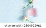 Perfume fragrance bottle on floral background. Top view of Transparent glass pink perfume bottle over rippled blue water background. splash of water. Flat lay, copy space