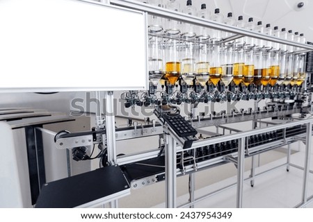 Perfume manufacturing process, overhead view of high tech filling bottles of aroma oil assembly line with yellow liquid of cosmetic.
