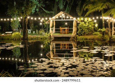 Pergola with glowing lights by the water. Gazebo with lights by the lake in late evening. Romantic scene in dusk. Patio romantic in the evening. Night gazebo, pavilion garden at night - Powered by Shutterstock