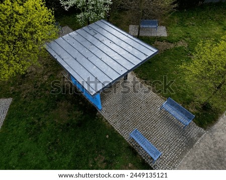 pergola of metal galvanized construction with blue planks in the side. under the shades there is a bench. city ​​shelter for lectures and concerts. public gazebo modern look