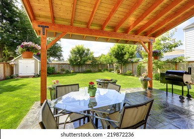 Pergola With Patio Area. Glass Top Table With Chairs, Fire Pit And Barbecue