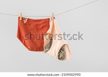Period panties and gypsophila flowers hanging on rope against grey background