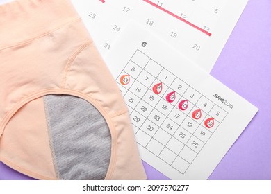 Period panties and menstrual calendar on color background, closeup