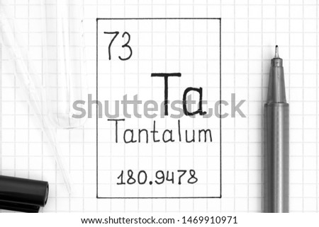 The Periodic table of elements. Handwriting chemical element Tantalum Ta with black pen, test tube and pipette. Close-up.