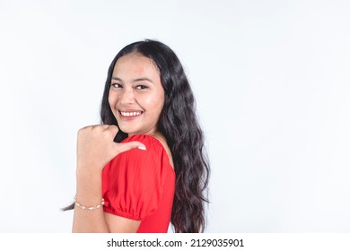 A perky and vivacious FIlipina woman in a casual red dress smiling and pointing to the right with her thumb. Isolated on a white background. Copyspace for advertising and promotion. - Shutterstock ID 2129035901