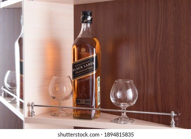 Perm, RUSSIA, January  2021. Bottle of Johnnie Walker Black Label Blended Scotch Whisky on shelf in bar, brown background with reflection. 