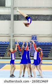 Perm, Russia - March 28, 2015. Championship Perm Krai On Cheerleading.  Girl In Blue White Suit Makes Element Flip  In  Group Stunt