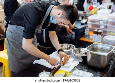 Perm, Russia - March 28, 2021: Festival MYAMI FEST. A Seafood Seller Prepares An Oyster For Serving. Fresh Oysters With Lemon On The Street Market.