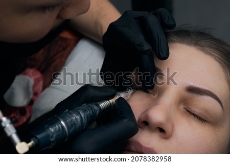 Permanent eyebrow makeup procedure. Eyebrow tattooing, process. The use of tools by a master for permanent eyebrow makeup