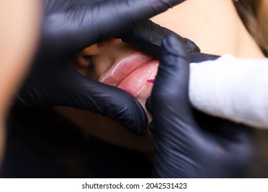 the permanent makeup artist performs the first pass of applying lip pigment