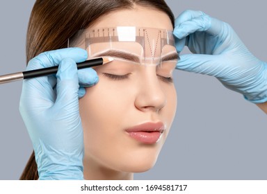 Permanent Make-up For Eyebrows Of Beautiful Woman With Thick Brows In Beauty Salon. Closeup Beautician Doing Tattooing Eyebrow. Professional Makeup And Cosmetology Skin Care.