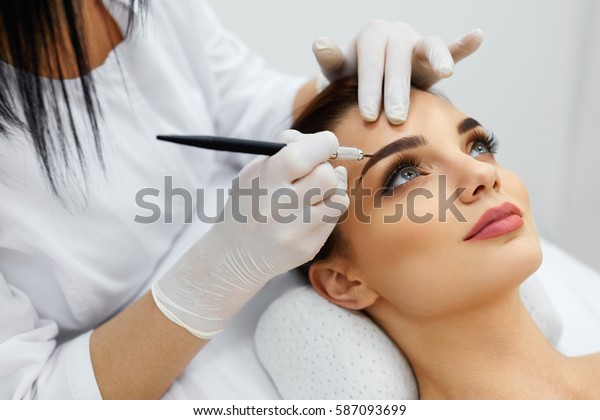 Permanent Makeup For\
Eyebrows. Closeup Of Beautiful Woman With Thick Brows In Beauty\
Salon. Beautician Doing Eyebrow Tattooing For Female Face. Beauty\
Procedure. High\
Resolution