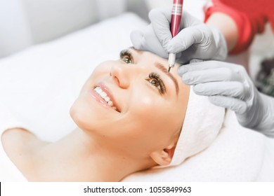 Permanent Makeup For Eyebrows. Microblading brow. Beautician Doing Eyebrow Tattooing For Female Face. Beautiful young girl in a beauty salon. Close up view of brown eyes with long eyelashes.