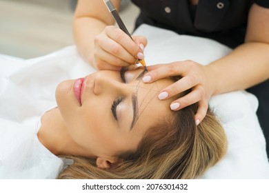  Permanent Makeup For Eyebrows. Microblading Brow. Beautician Doing Eyebrow Tattooing For Female Face. Beautiful Young Girl In A Beauty Salon 