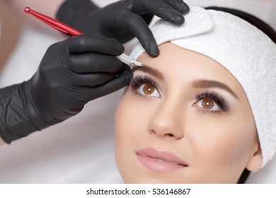 Permanent makeup eyebrows. Mikrobleyding eyebrows workflow in a beauty salon. Cosmetologist applying a special permanent makeup on a woman's eyebrows.