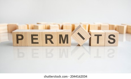 permits - word of wooden blocks with letters on a gray background. Reflection of the caption on the mirrored surface of the table. Selective focus.