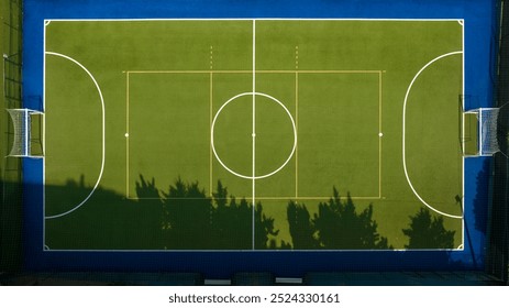 Perpendicular aerial view of an empty five-a-side football pitch. It has a synthetic grass pitch but there is no one in the sports centre.